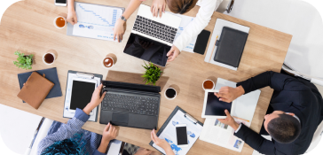People working on laptops at a table, collaborating and focusing on their tasks.
